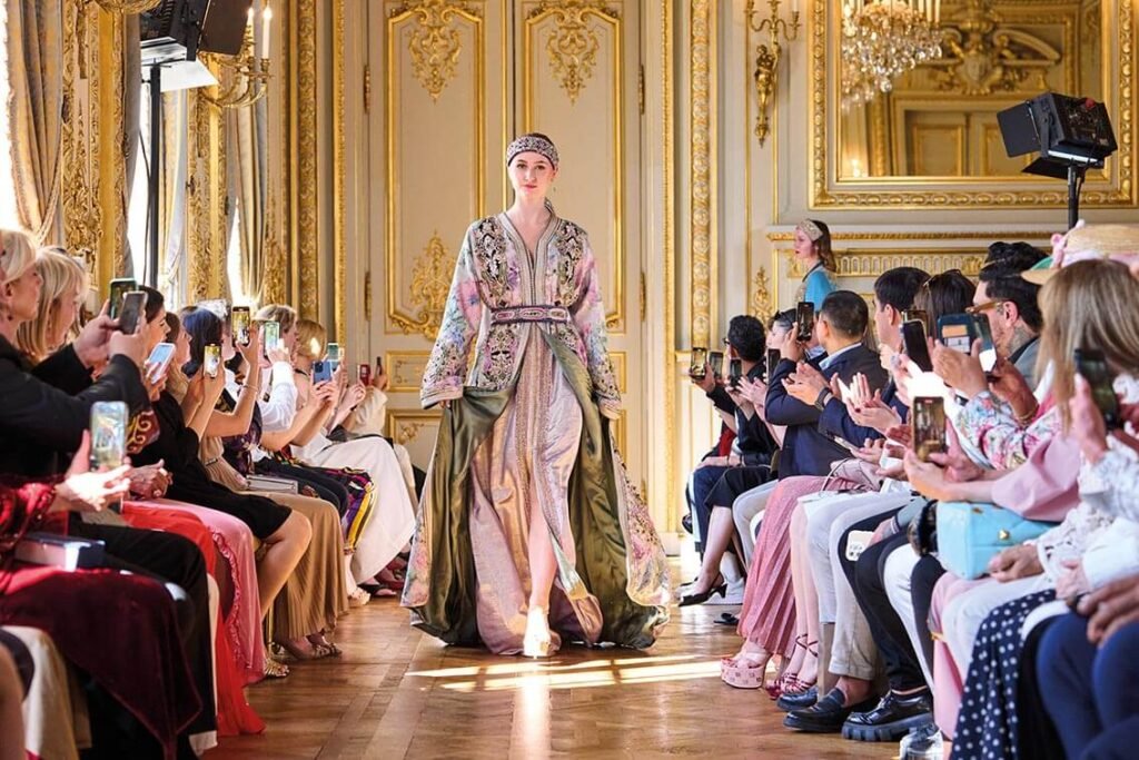 Une femme défile à la fashion week en caftan au Palais de Versailles. L'origine du caftan étant marocaine, cet évènement a été perçu comme un hommage à la culture marocaine. Majestia, spécialiste de la location de caftan en France.